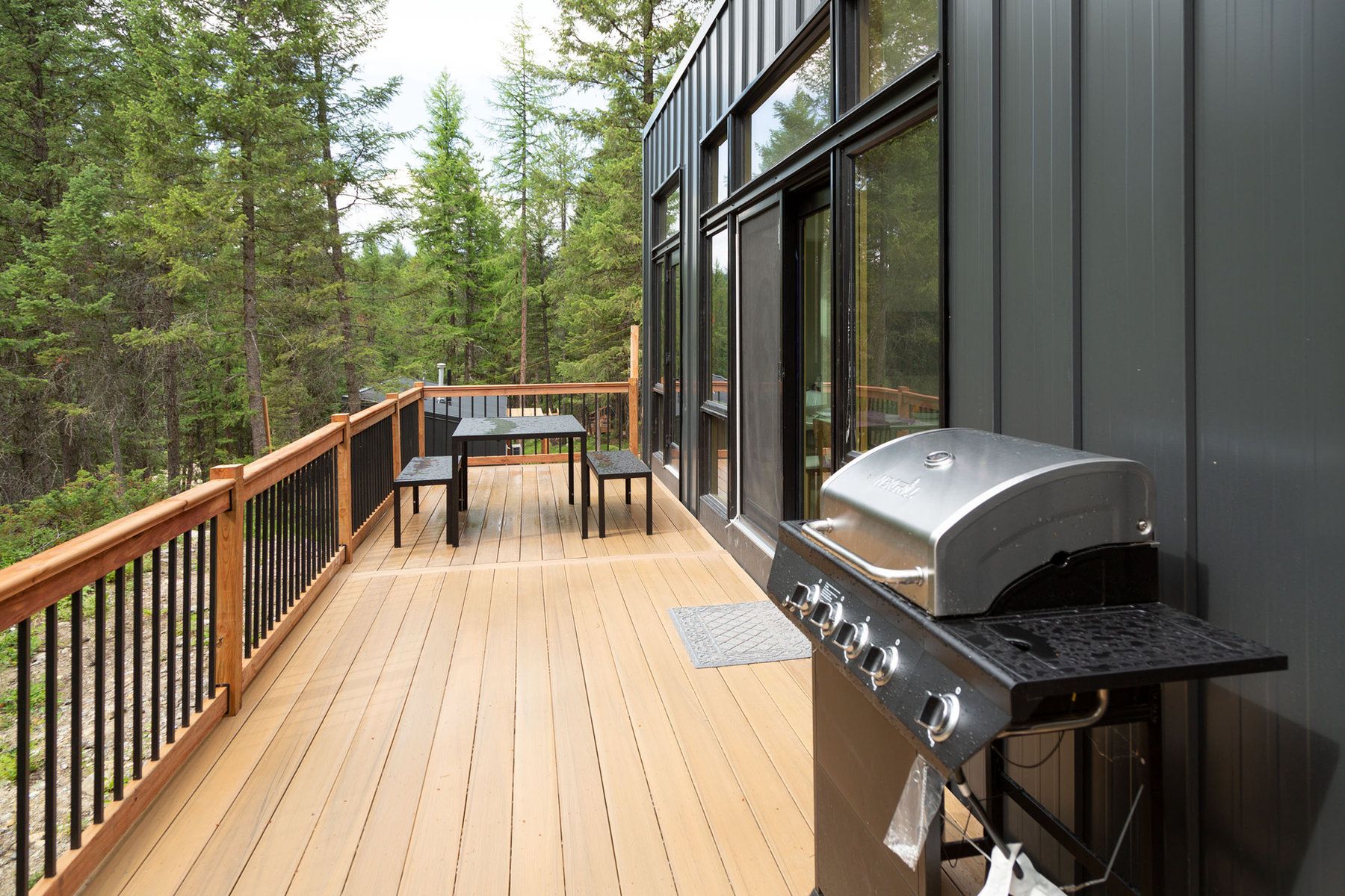 Cabin deck with a grill and outdoor dining table among the pines at North Star Ranch