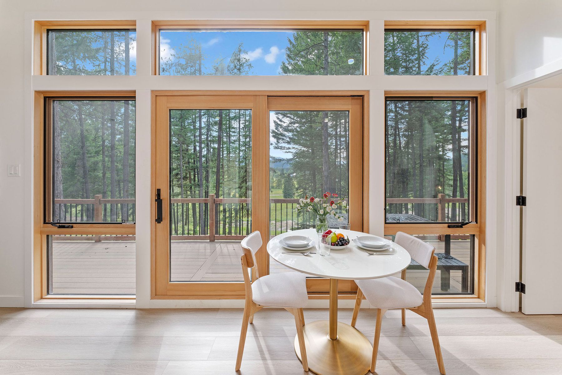 Bright cabin dining area with forest views through tall windows at North Star Ranch