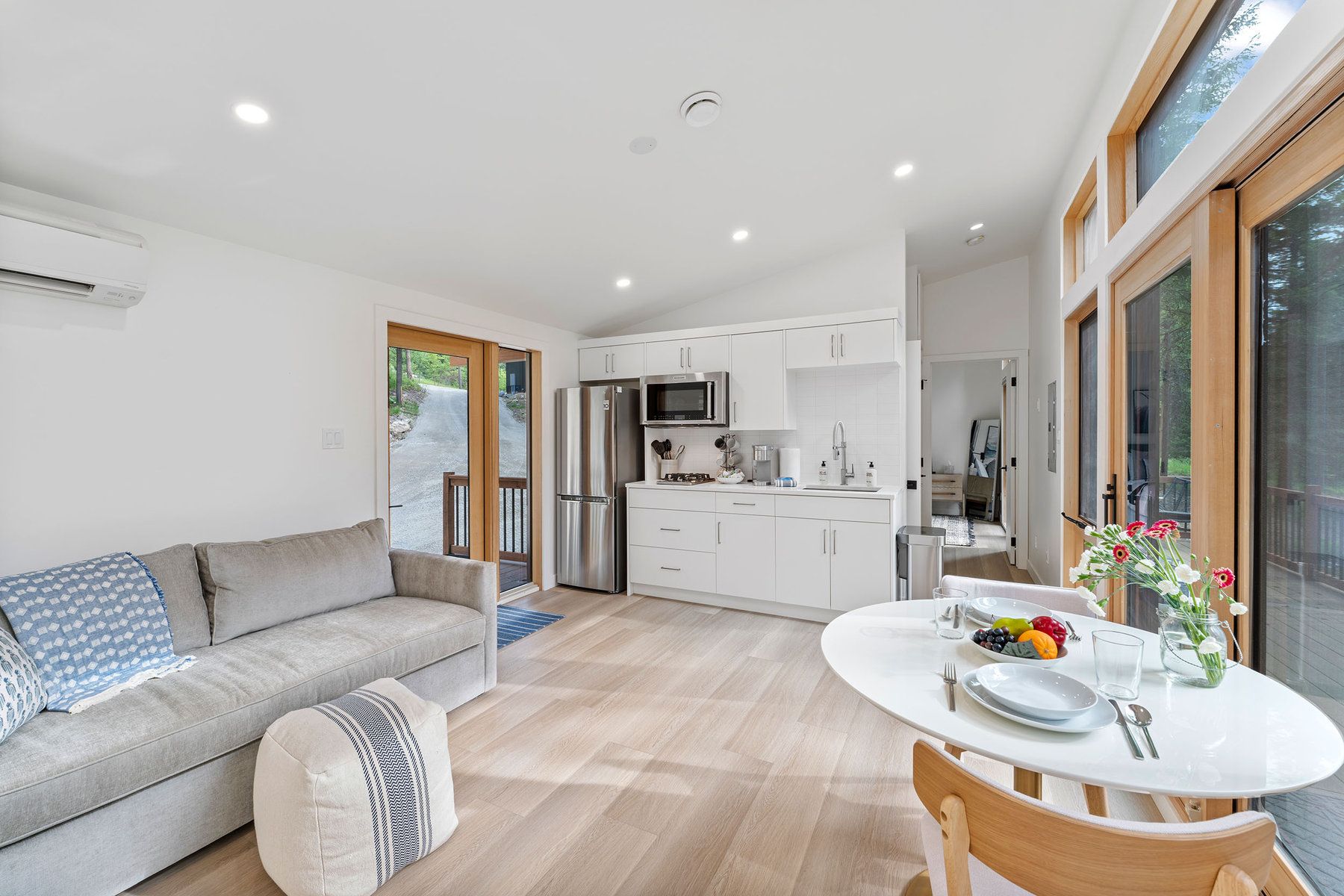 Bright cabin living room and kitchenette with forest views at North Star Ranch