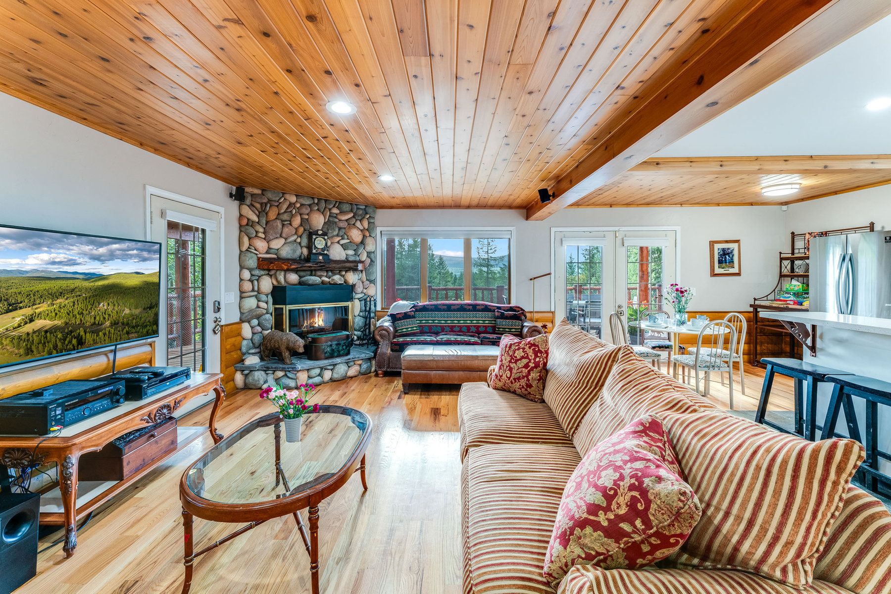 Open chalet living room with a stone fireplace, sofas and a dining table at North Star Ranch