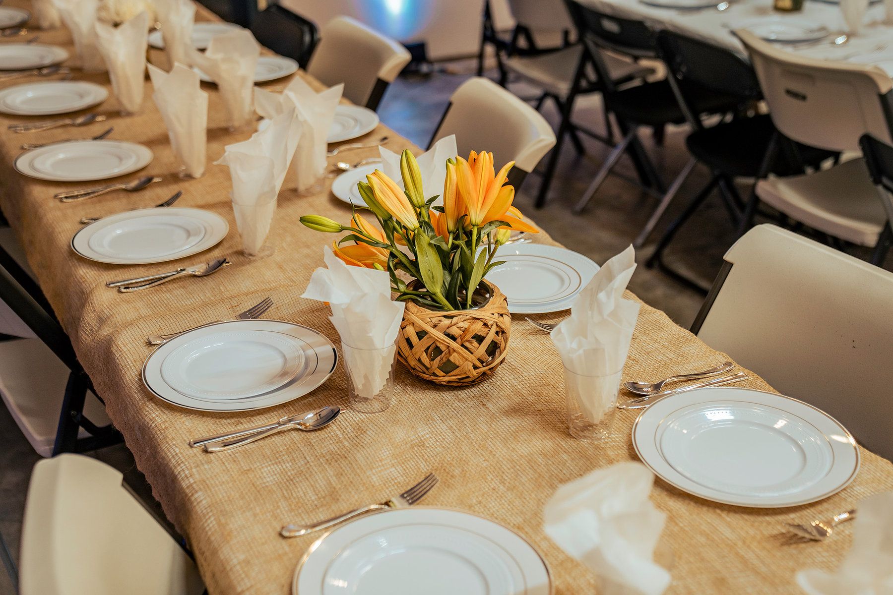 Long dinner table set with plates, napkins and orange lilies at North Star Ranch